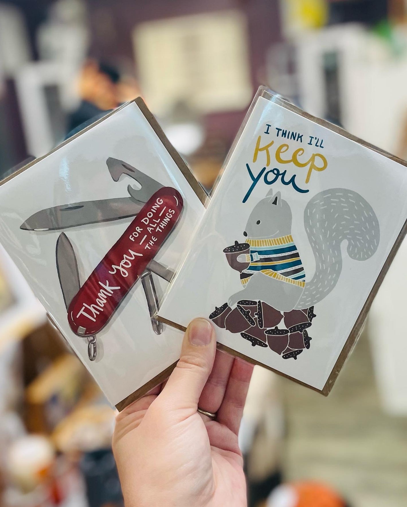 Image shows two greeting cards. One reads "thanks for doing all the things", with a graphic of a swiss army knife, and the other reads "I'll keep you" with a cute graphic of a squirrel holding a nut.