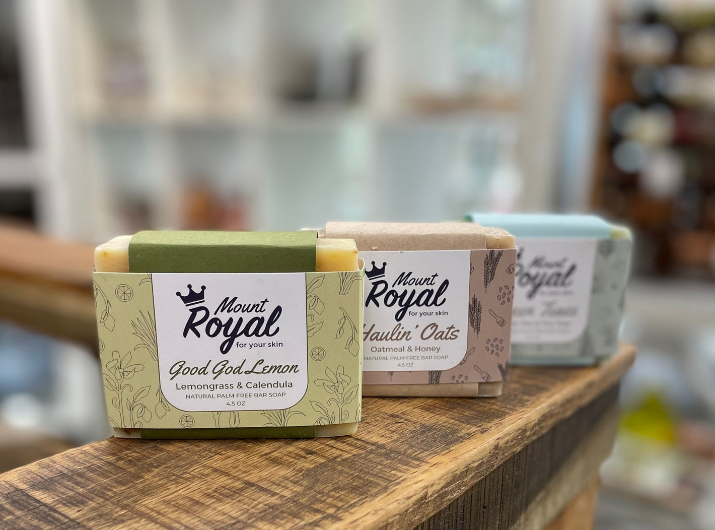 Image shows three soaps lined up. The soaps are yellow, brown and blue, and the scents printed on their labels are Lemon, Haulin' Oats and Green Teese